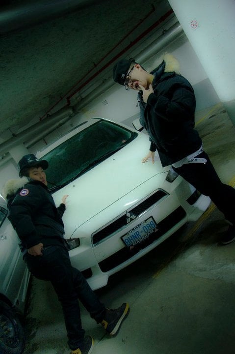Jason and a friend posing on a white car in a parking garage, circa 2011